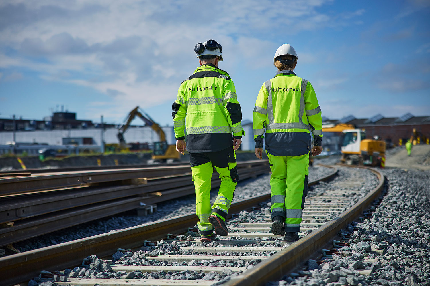 To personer som går på jernbaneskinner på byggeplass