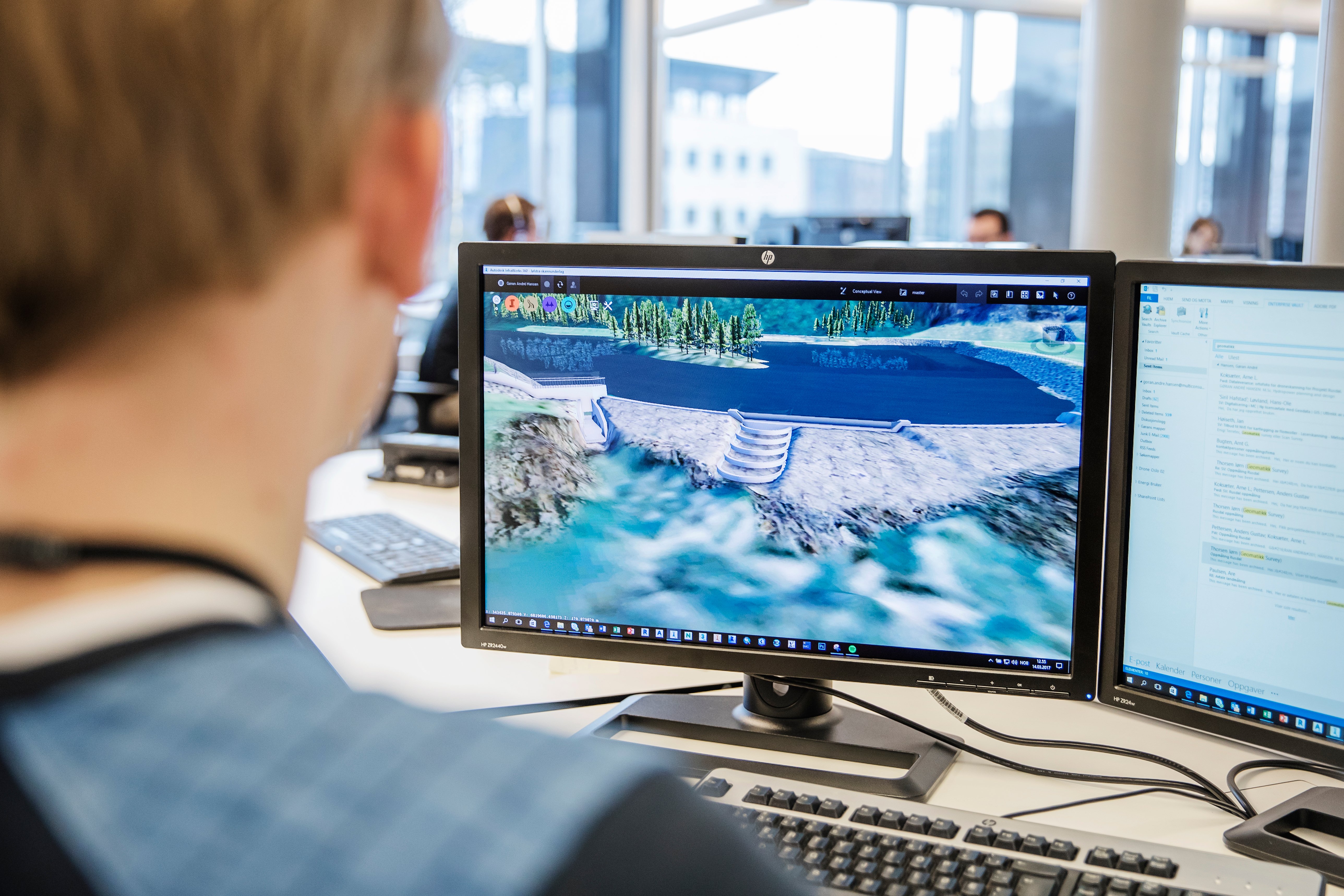 Mann foran to skjermer, en skjerm viser modeller av en demning