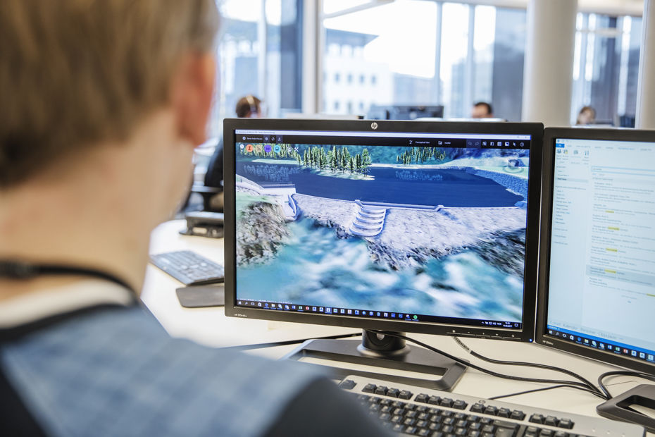 Mann foran to skjermer, en skjerm viser modeller av en demning